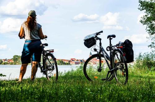 a woman standing next to two bikes in the grass at Oase am See - Ferienwohnung mit Blick auf die Müritz in Waren