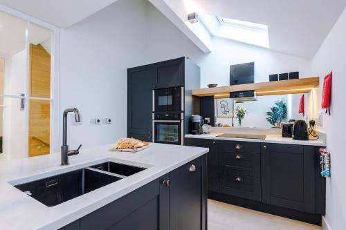 a kitchen with black cabinets and a sink at King Street Collection in Manchester