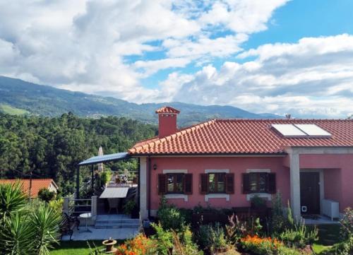 a house with a red roof with mountains in the background at Travessia do Sol - Eco Lodge and Retreat Centre in Gemieira