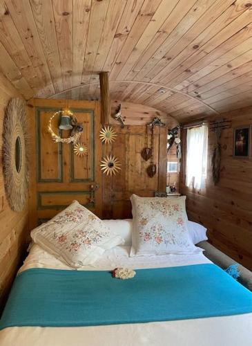 un lit dans une chambre avec un plafond en bois dans l'établissement Roulotte insolite U tragulinu, à Zonza