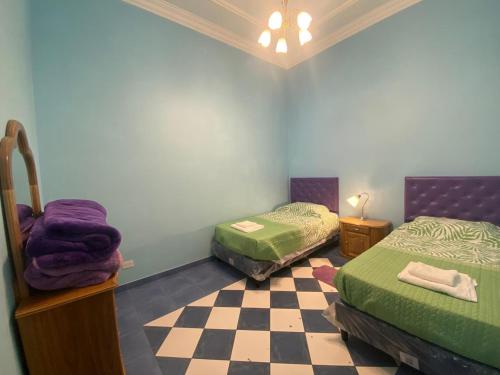a bedroom with two beds and a checkered floor at Casa en centro salteño in Salta