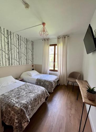 a bedroom with two beds and a tv and a window at BO LODGE in Le Bourg-dʼOisans