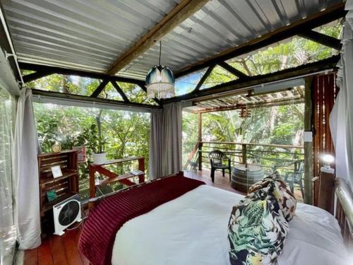 a bedroom with a large bed on a porch at Mantis and Moon Surf Paradise & Adventure Lodge in Hibberdene