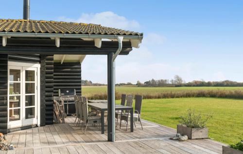 Dannemareにある3 Bedroom Awesome Home In Dannemareのデッキにテーブルと椅子が置かれたパティオ