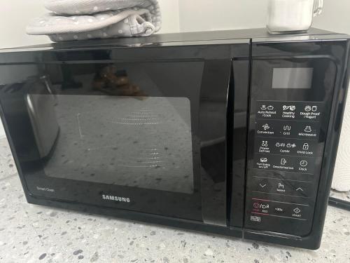 a black microwave oven sitting on a counter at Little Ings, Modern, idyllic, self-contained hideaway in Easingwold, North Yorkshire in Easingwold