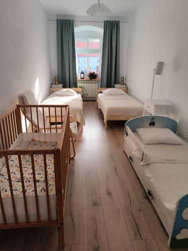 a room with three bunk beds and a window at Apartament pod Wieżą Srebrna Góra in Srebrna Góra
