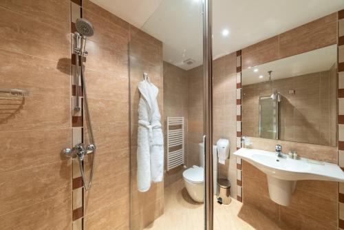 a bathroom with a shower and a sink and a toilet at Terra Hotel in Bansko