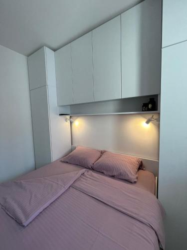 a bedroom with a bed with purple sheets and white cabinets at Apartman 21 Banja Koviljača in Banja Koviljača