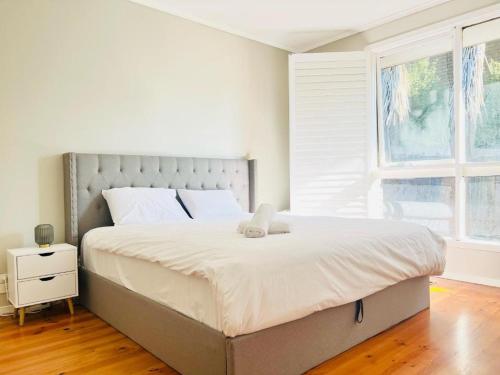 a bedroom with a large bed with white sheets and a window at Villa pool garden in Melbourne