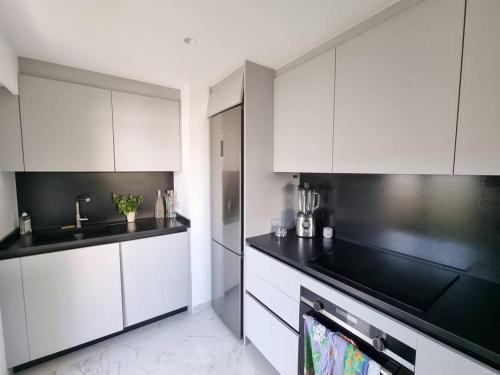 une cuisine avec des armoires blanches et des comptoirs noirs dans l'établissement 85m2 Grandes Terrasses - 2 chambres, à Cannes