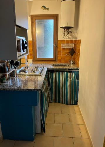 une cuisine avec un comptoir, un évier et une fenêtre dans l'établissement Appartamento con giardino a 50 m dal mare, à LʼÎle-Rousse