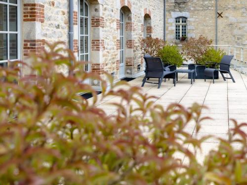 a patio with chairs and a table in a building at Hôtel Ginkgo - SPA Biloba in Quimper