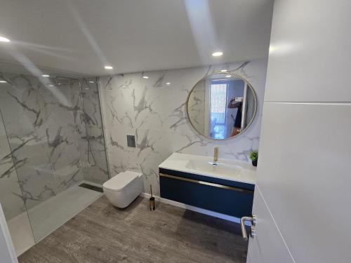 a bathroom with a sink and a toilet and a mirror at Ocean Paradise de Santa Luzia in Funchal