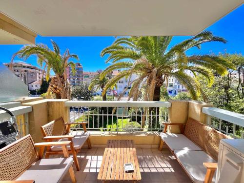 d'un balcon avec des chaises, une table et des palmiers. dans l'établissement LE TRAVOLTA avec merveilleuse terrasse, chic et lumineux à deux pas du centre-ville, à Cannes