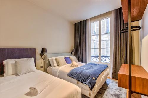 deux lits dans une chambre avec une fenêtre dans l'établissement Urban Flat 111 - Urban Lovely Flat Madeleine, à Paris