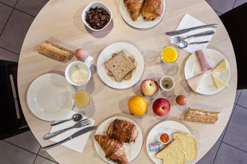a table with plates of breakfast foods on it at Ace Hotel Annemasse Genève in Ville-la-Grand