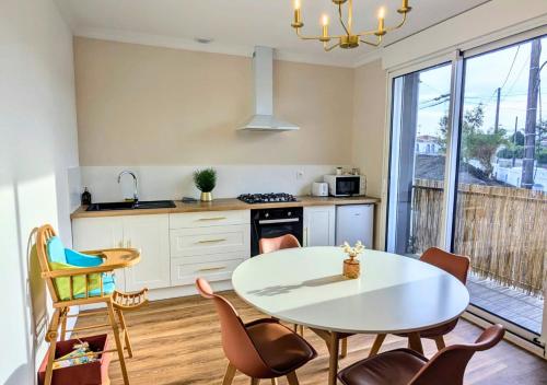 une cuisine avec une table et des chaises blanches ainsi qu'une table et une table dans l'établissement Solen Évasion - Calypso - Vacances en Vendée, à Aizenay