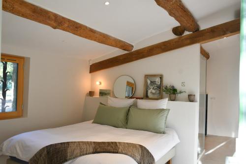 - une chambre avec un lit blanc et des oreillers verts dans l'établissement La Piscine dans la Foret, à Gordes