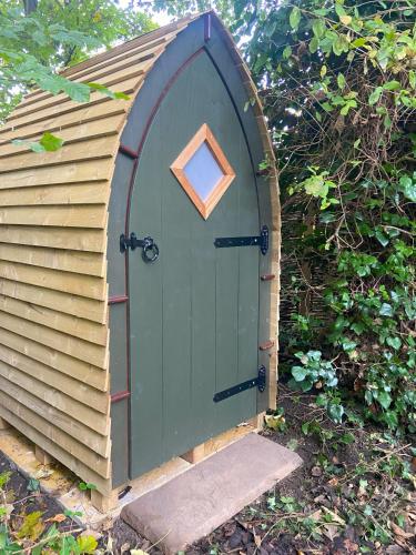 a green door with a window in a garden at Stamford Meadows Glamping with Private Hot Tubs in Stamford