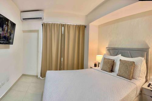 a bedroom with a white bed and a window at Comfy 2BR City Center Condo in Los Prados