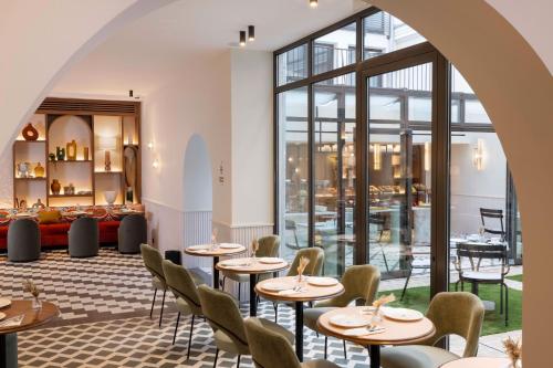a restaurant with tables and chairs and a large window at Hotel Grand Coeur Latin in Paris
