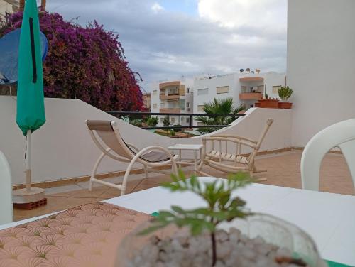 a balcony with a table and chairs and a green umbrella at superbe appartement Al Mansouria-les jardins de l'Atlantique in Pont Blondin