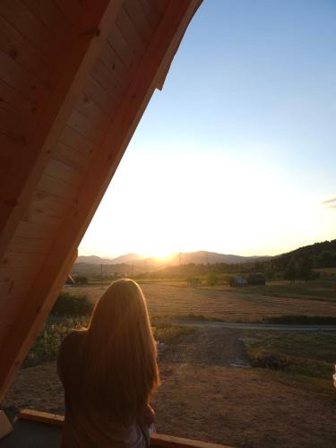 a woman looking out a window at the sunset at Sunflower House Radoinja in Nova Varoš