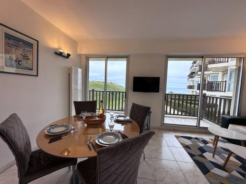 une salle à manger avec une table et des chaises et un balcon dans l'établissement Entre Dunes et mer - Accès privé à la mer, à Cabourg