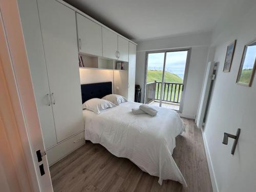 a white bedroom with a bed and a balcony at Entre Dunes et mer - Accès privé à la mer in Cabourg