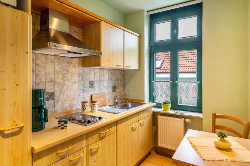 a kitchen with wooden cabinets and a sink and a table at Fewo Altstadtkern Waren Müritz in Waren