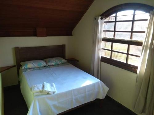 una camera da letto con un letto bianco con una finestra di Casa Vivenda dos Bem-te-vis a Monte Verde