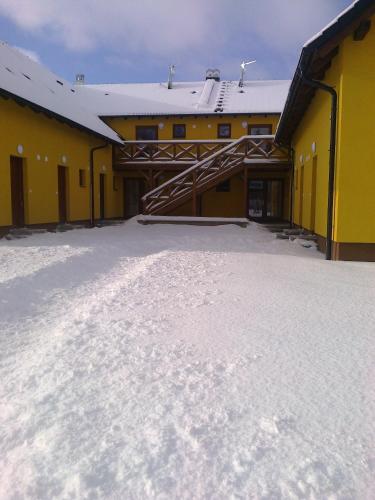 a building with snow on the ground in front of it at Apartmán s terasou a výhledem na jezero Lipno in Kovářov