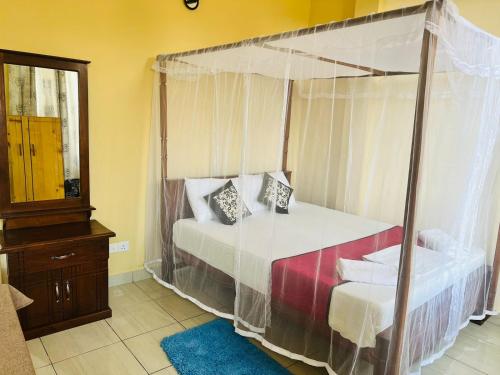 a bedroom with a canopy bed and a mirror at New Golden Bay Resort Weligama in Weligama