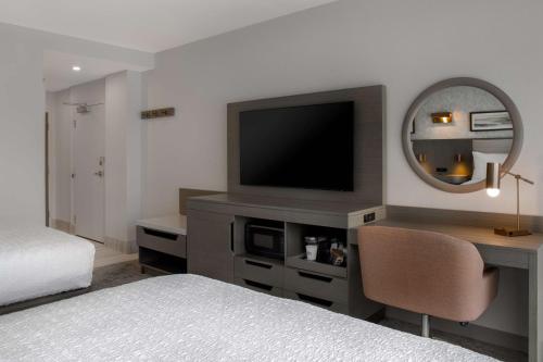 a bedroom with a bed and a desk with a television at Hampton Inn By Hilton Winnipeg Downtown in Winnipeg