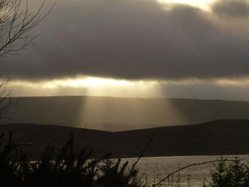 a stormy sky with the sun shining through the clouds at Aultbea Lodges in Aultbea