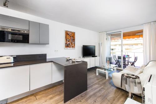 une cuisine avec des armoires blanches et un salon dans l'établissement AIGLON - Agréable 2 pièces - 50 m du bord de mer, à Roquebrune-Cap-Martin