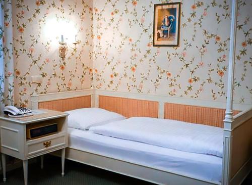 a bedroom with a bed and a nightstand with a bed sidx sidx at Hotel Hohenstauffen in Salzburg