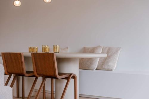 een eettafel met stoelen en een witte muur bij Huswell - Luxurious apartment on top location in Knokke in Knokke-Heist