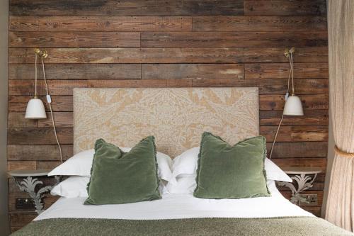a bedroom with a bed with green pillows at The Stag at Stow in Stow on the Wold