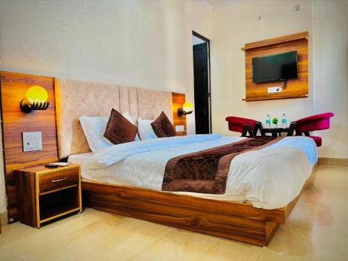 a bedroom with a large bed and a flat screen tv at Trinetra Guest House in Rishīkesh
