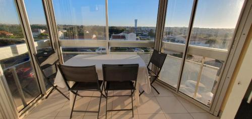 d'une table et de chaises blanches sur un balcon avec fenêtres. dans l'établissement Bulle O 50 m de la plage, à Saint-Gilles-Croix-de-Vie
