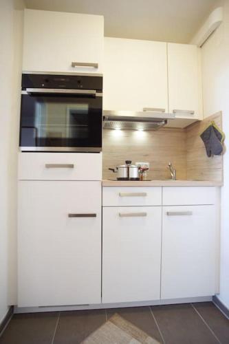 a kitchen with white cabinets and a stove at Surforama Apartment Meerblick am Südstrand in Fehmarn