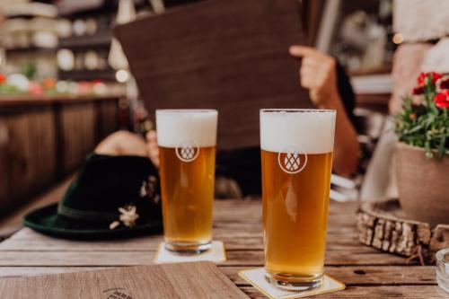 two glasses of beer sitting on a wooden table at Martinerhof's Brauhotel in San Martino
