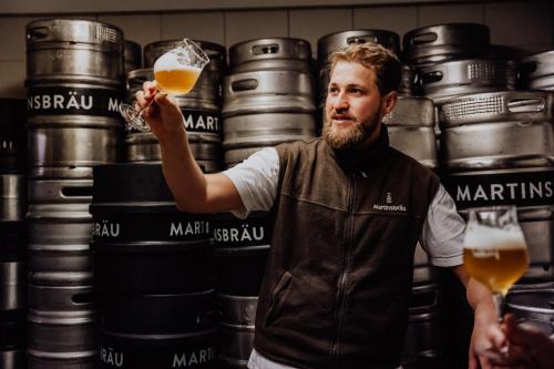 a man holding up a glass of beer at Martinerhof's Brauhotel in San Martino