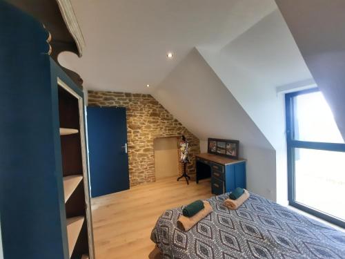 - une chambre mansardée avec un lit et un bureau dans l'établissement Charmante maison au cœur de la forêt, à Baguer-Morvan