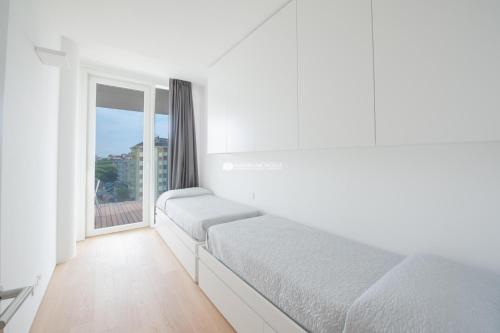 Una habitación blanca con una cama y una ventana. en The Summer Houses Immobiliare Pacella, en Lido di Jesolo