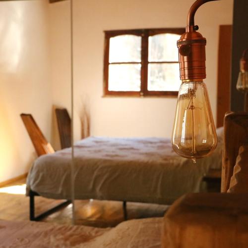 a bedroom with a bed and a light fixture at Hostal SPA Casa de Piedra in La Quebrada