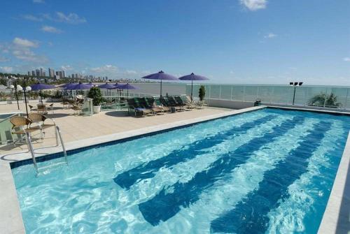 a large blue swimming pool with chairs and umbrellas at Blue Sunset Suites in Penha
