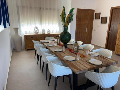 a long wooden table with white chairs and a vase on it at Villa Palms de l'Atlas in Marrakech