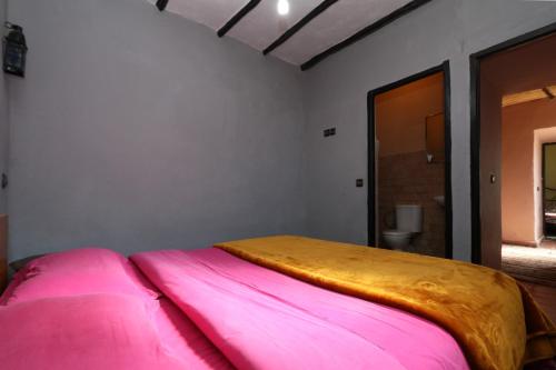 a bedroom with a large bed with pink sheets at Gite Ogog Tacheddirt in Tacheddirt